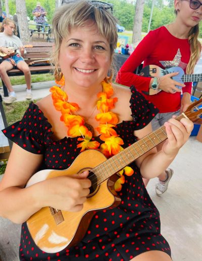 Woman wearing lei strumming a ukulele