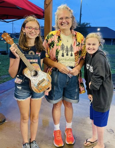 Woman and two younger girls posing with colorful ukulele