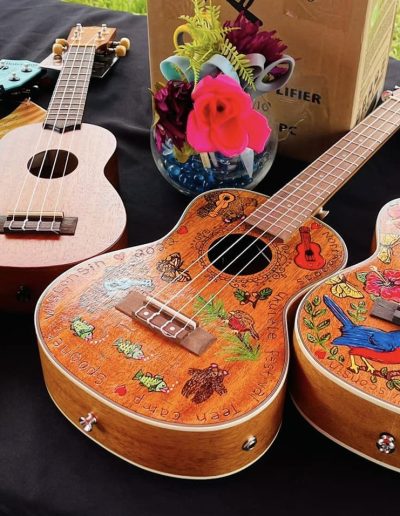 Six colorful ukuleles on a table with a black tablecloth
