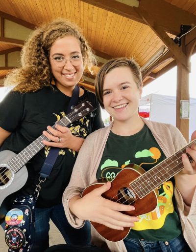 two young women posing with a ukulele each
